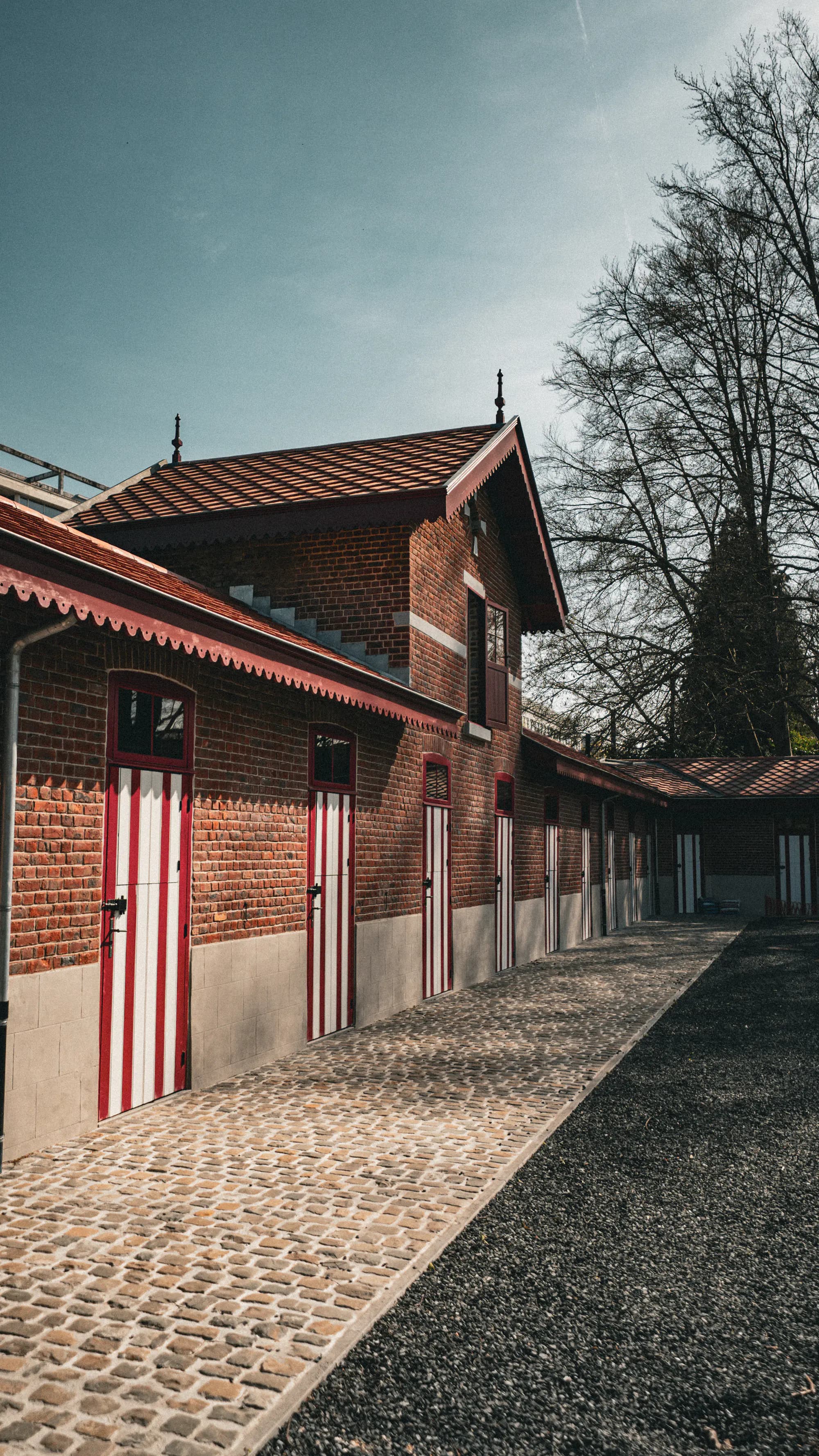 Les écuries néo-Renaissance de 1875 — entrée latérale, portes à rayures rouges et blanches